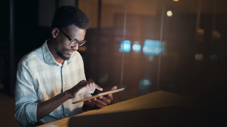 A man sitting on the desk with a tablet in the hand